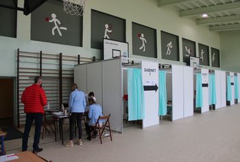 Punkt Szczepień Powszechnych - sala gimnastyczna, na której znajdują się 3 parawany przeznaczone do szczepień. Z lewej strony biurko przy którym znajduje się punkt informacyjny